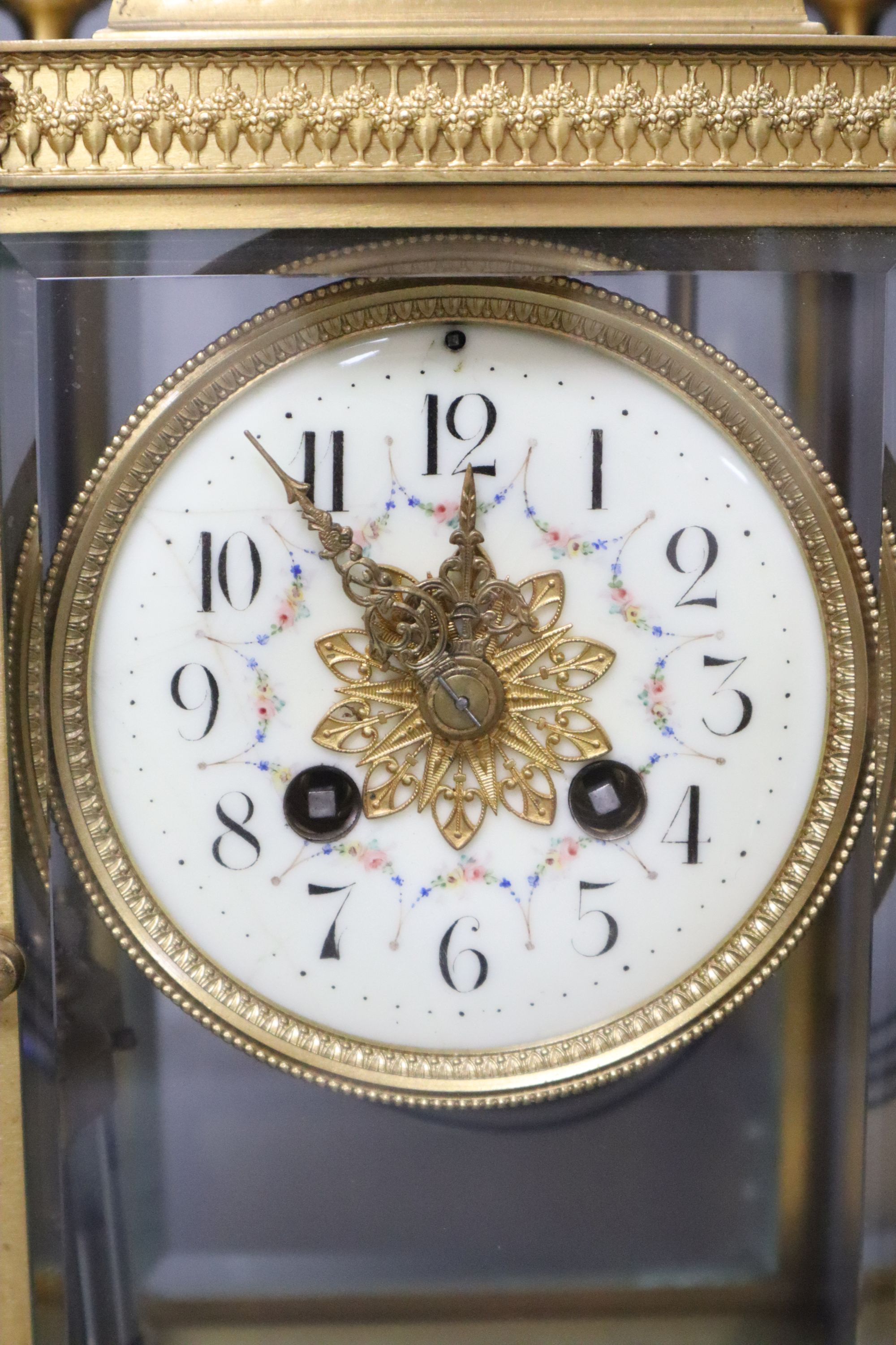 A late 19th century French garniture de cheminée comprising a four-glass mantel clock and a pair of vases